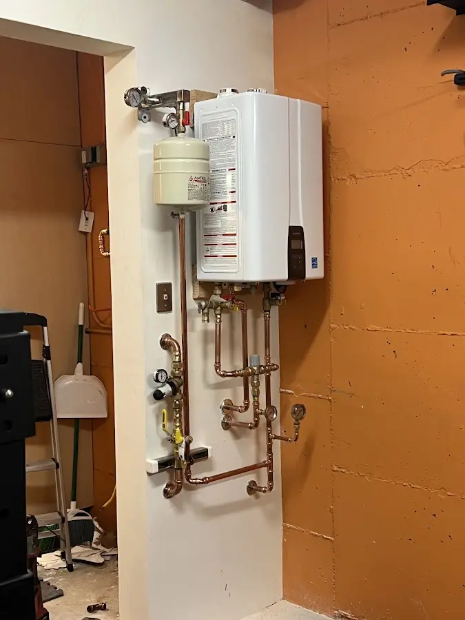Plumbing technician inspecting water heater connections in Lake Grove